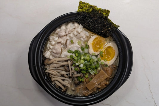 One-pot Nissin Demae Iccho Kyushu Tonkotsu bar noodles served directly in a pot topped with pork belly, shimeji mushrooms, and jammy soy-marinated egg