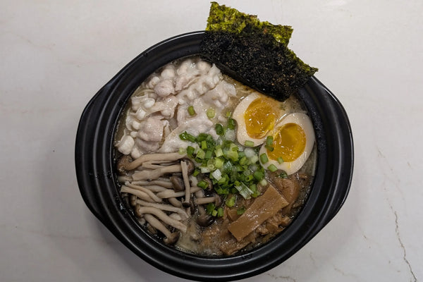 One-pot Nissin Demae Iccho Kyushu Tonkotsu bar noodles served directly in a pot topped with pork belly, shimeji mushrooms, and jammy soy-marinated egg