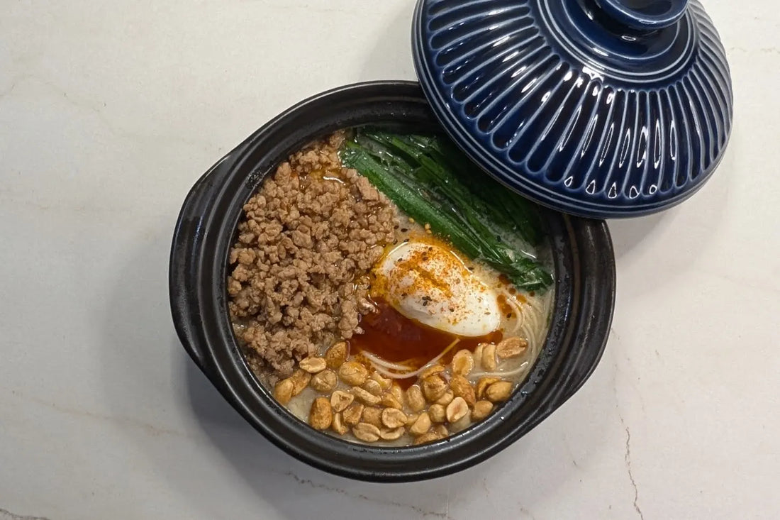 Spicy Aka Tonkotsu ramen in a clay pot topped with poached egg, ground pork, fresh chives, and peanuts