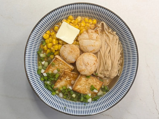 10-Minute Hokkaido Miso Tonkotsu Ramen topped with butter-seared scallops, pan-fried tofu, enoki mushrooms, sweet corn, and a melting pat of butter in a black bowl.