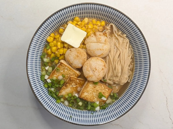 10-Minute Hokkaido Miso Tonkotsu Ramen topped with butter-seared scallops, pan-fried tofu, enoki mushrooms, sweet corn, and a melting pat of butter in a black bowl.